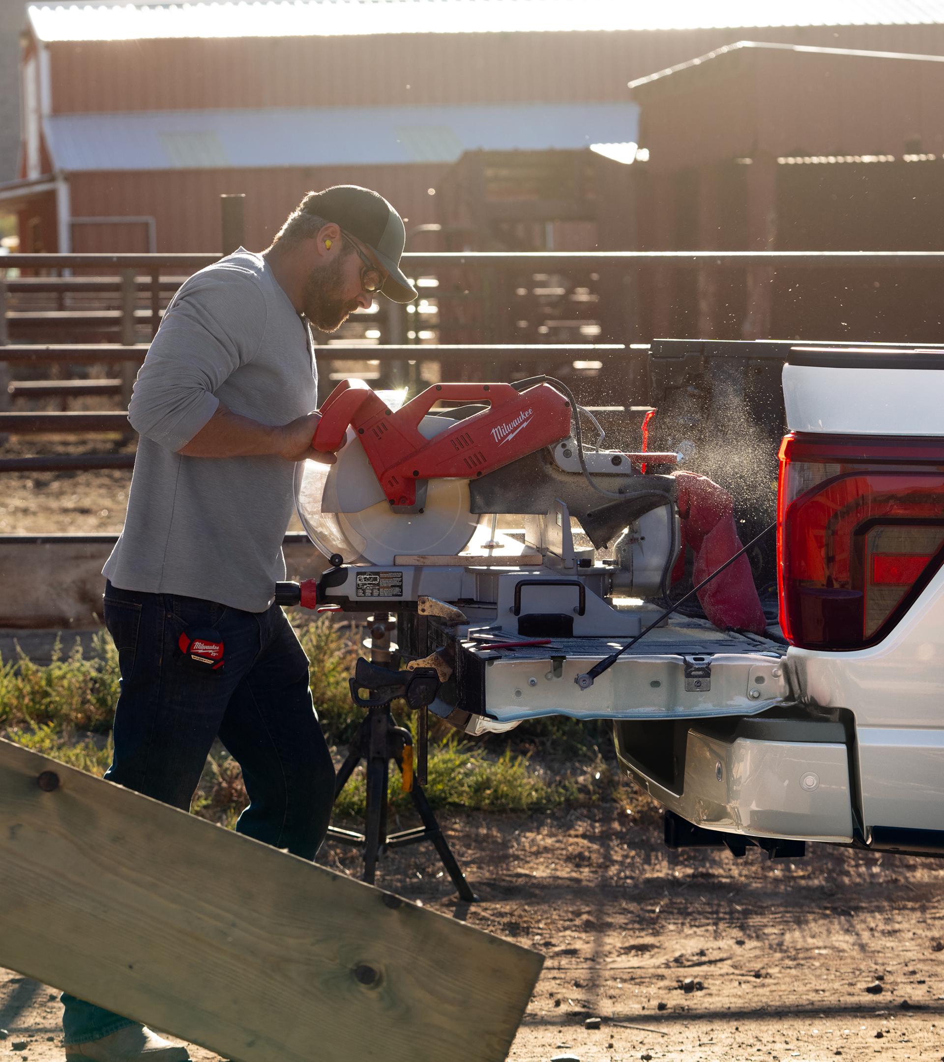 Homme utilisant une scie à onglets sur le hayon d’un camion Ford F-150® 2026 alors qu’elle est branchée à la fonction Pro Power embarquée