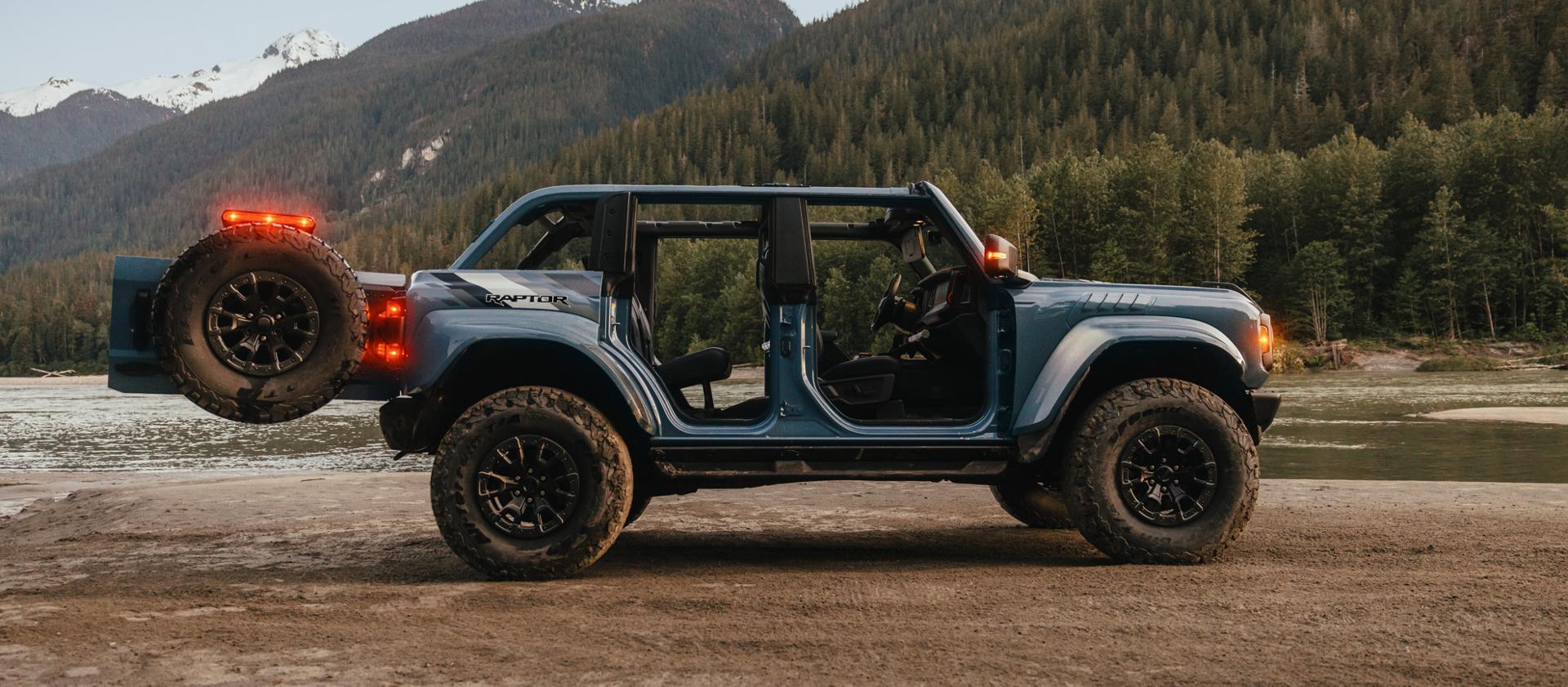 Un VUS Ford Bronco® 2025 avec les portes retirées et le hayon ouvert, stationné sur une vasière près d’un lac de montagne