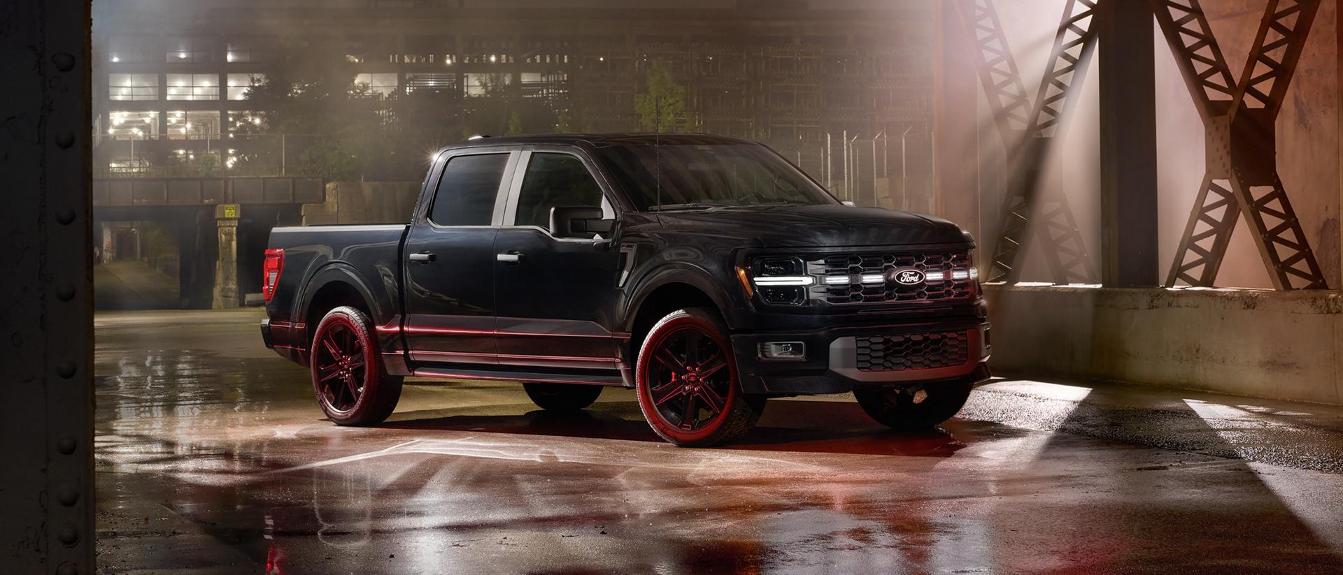 Un Ford F-150® STX 2025 noir avec l’ensemble Lobo™, stationné dans une rue vacante de la ville la nuit