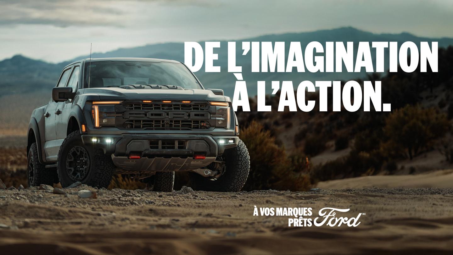 Vue avant trois quarts d’un Ford F-150 Raptor stationné sur de la terre avec des montagnes en arrière-plan. « Rêvez-le. Poursuivez-le. Prêt, pas prêt, Ford. »