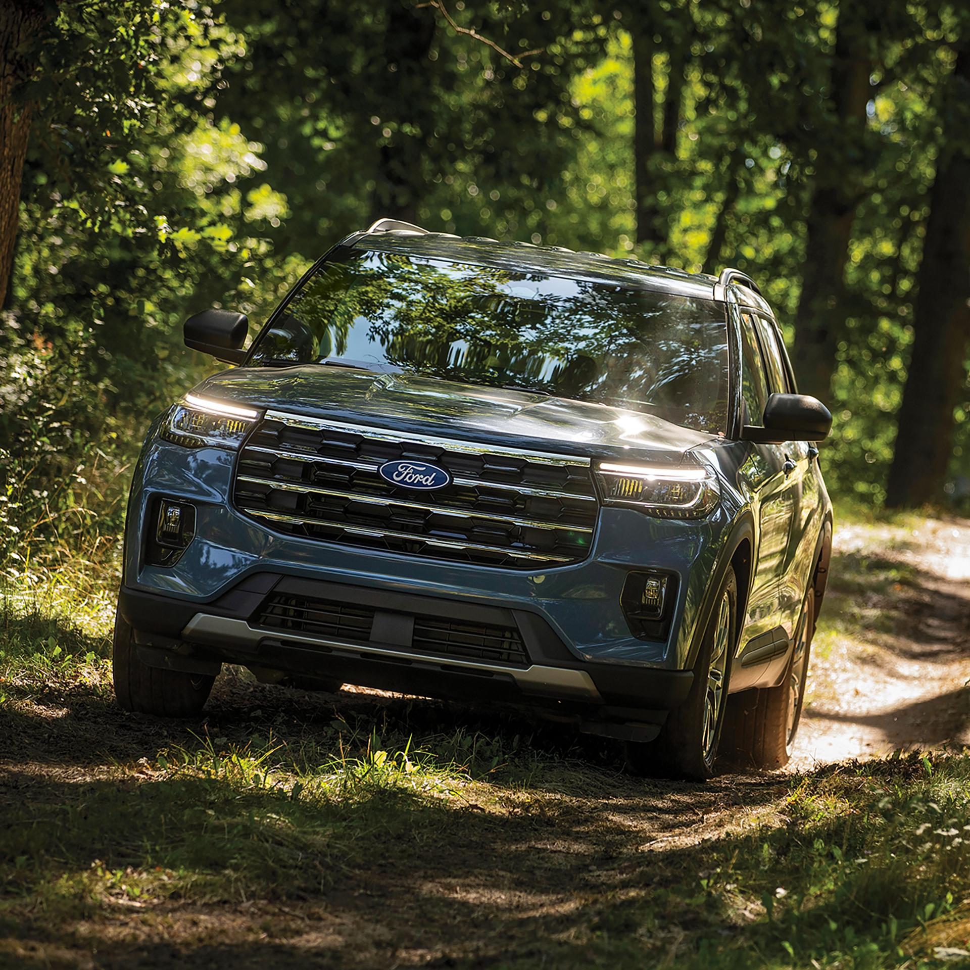 Un VUS Ford Explorer® 2027 roulant sur un sentier de terre à travers la forêt