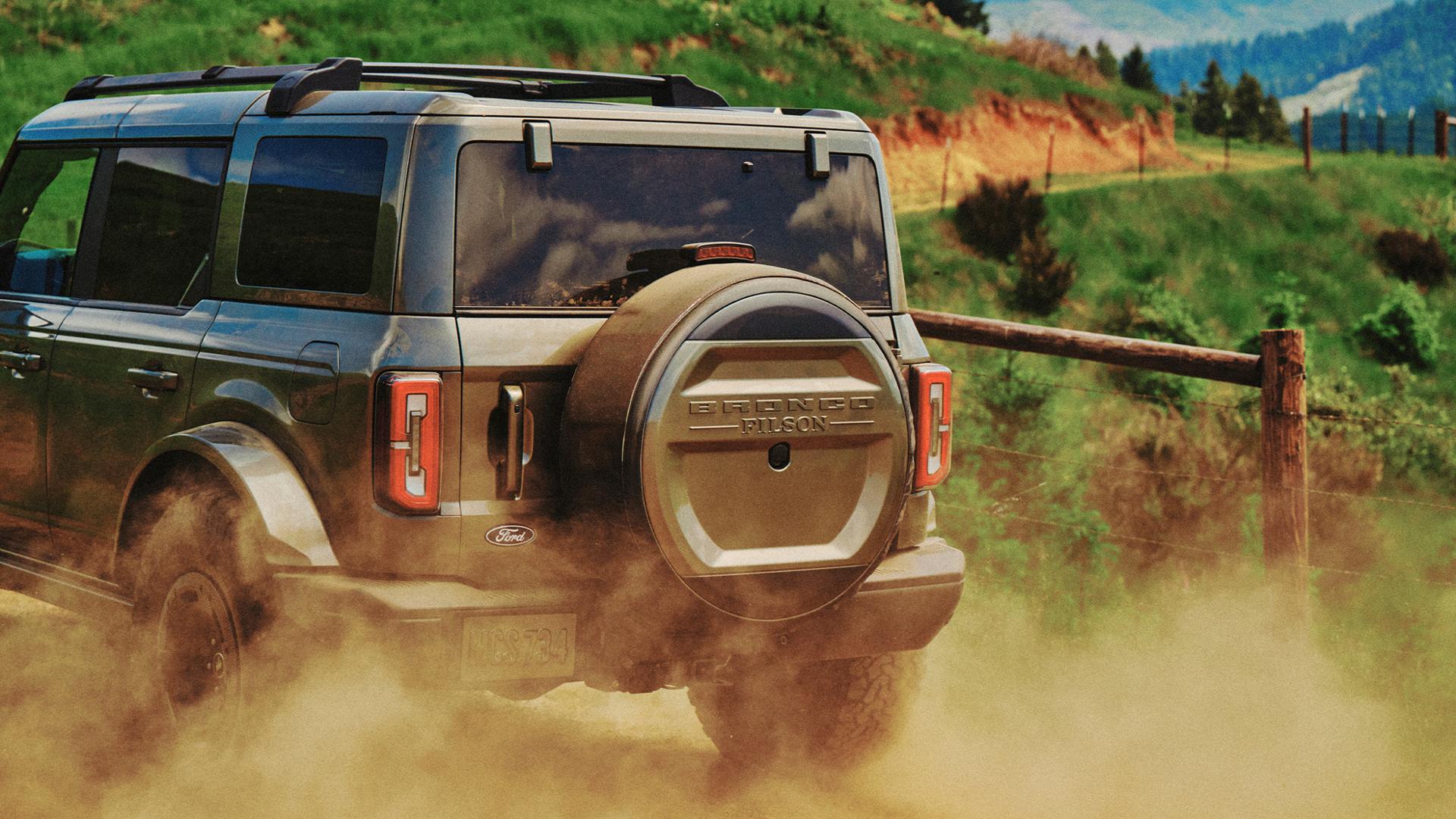 Un VUS Ford Bronco® Filson 2027 soulève de la poussière sur un chemin de terre