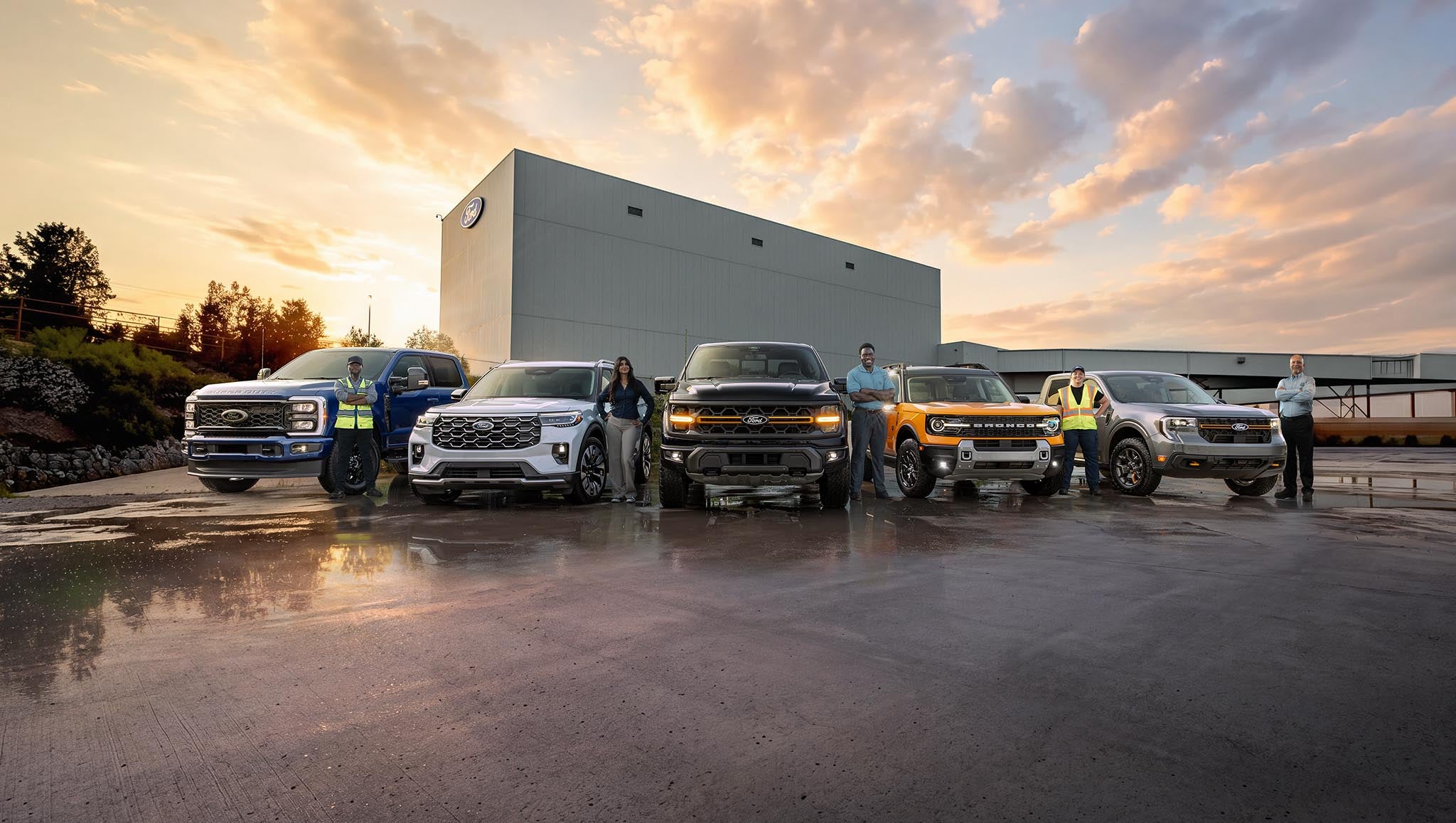 Des employés de Ford debout près de véhicules Ford stationnés devant l’usine d’assemblage Ford d’Oakville.
