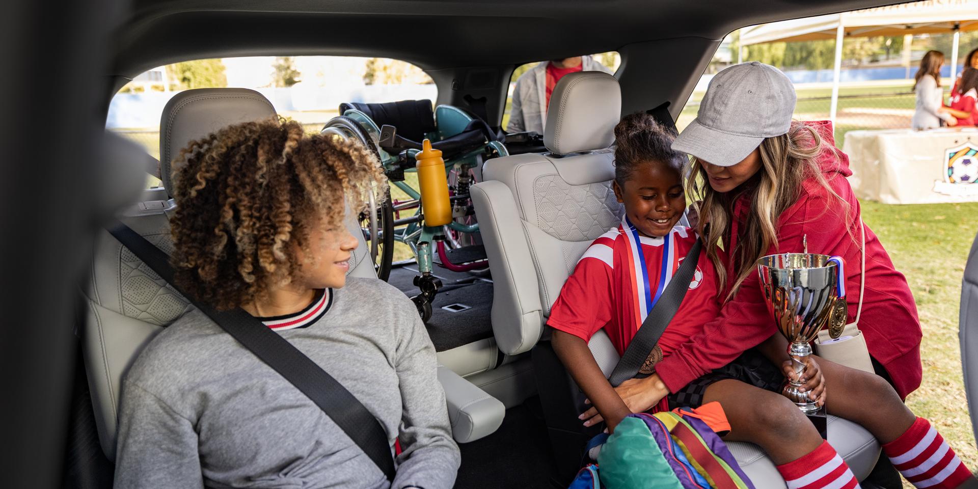 Un parent aidant à installer de jeunes joueurs de soccer sur les sièges de deuxième rangée d’un VUS Ford Explorer® 2027
