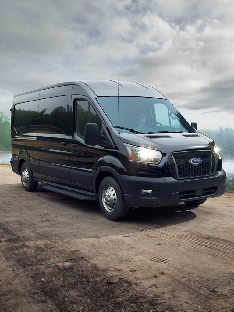 Une fourgonnette Ford Transit® 2026 conduit sur une route rurale