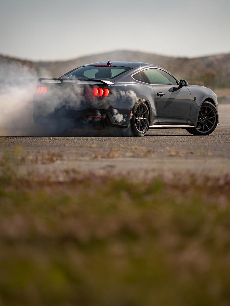 Ford Mustang Dark Horse® Coupé 2026 en bleu vapeur métallisé avec un conducteur professionnel faisant crisser ses pneus sur un parcours fermé
