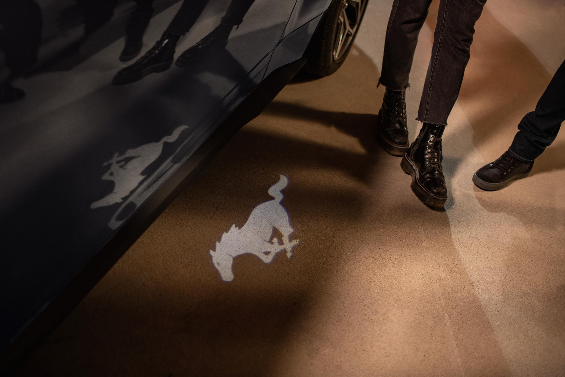 Logo Mustang au sol près d’une Mustang noire.