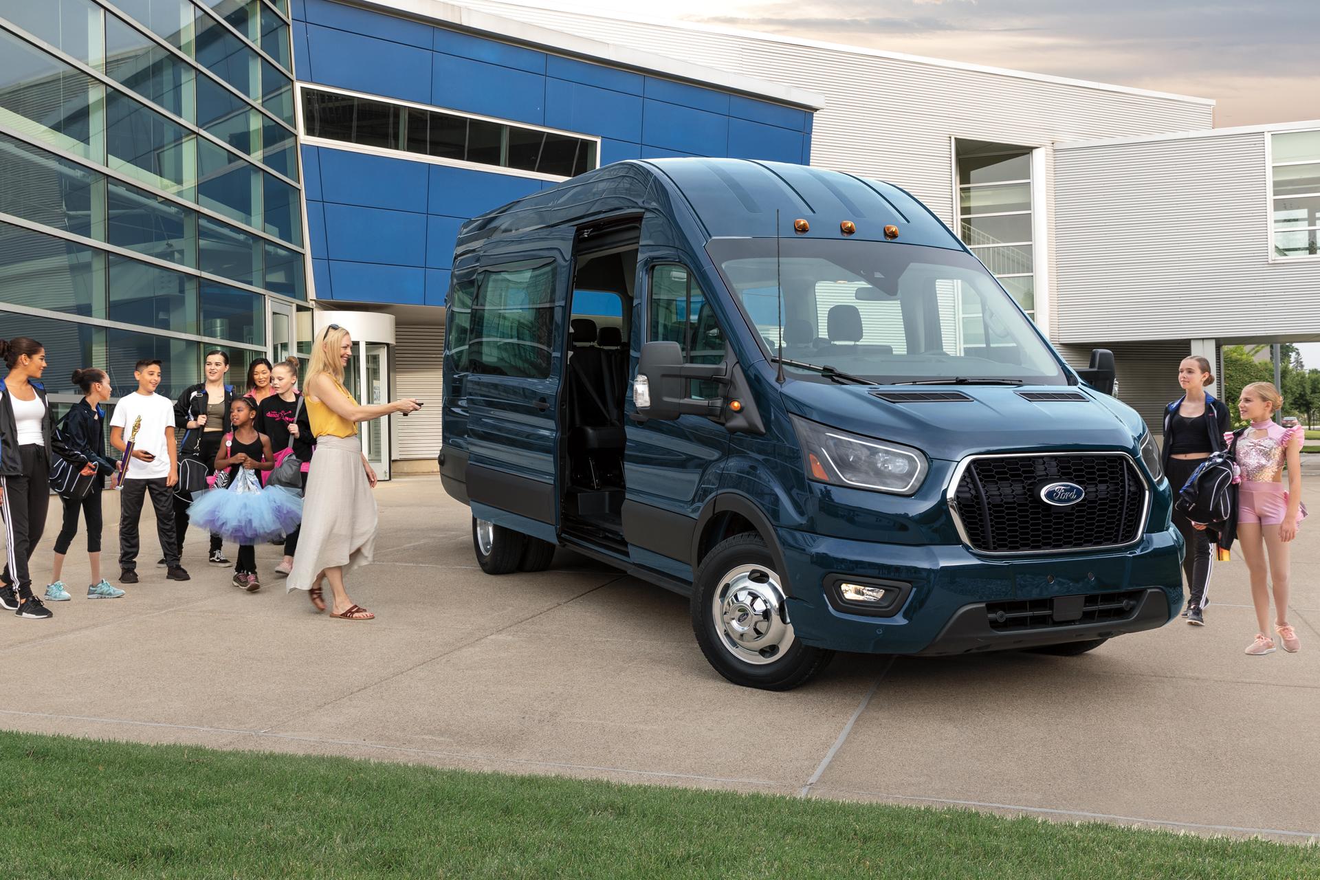 Une fourgonnette Ford Transit® 2026 avec la portière latérale ouverte, entourée d’un groupe de personnes
