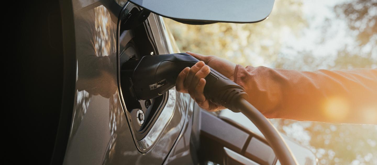 Le port de recharge d’un camion Ford F-150® Lightning 2025 avec une main tenant la fiche du chargeur