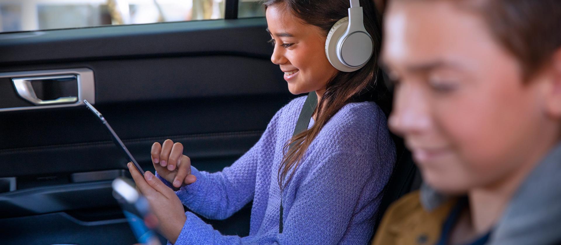 Enfants utilisant des appareils mobiles sur la banquette arrière d’un véhicule