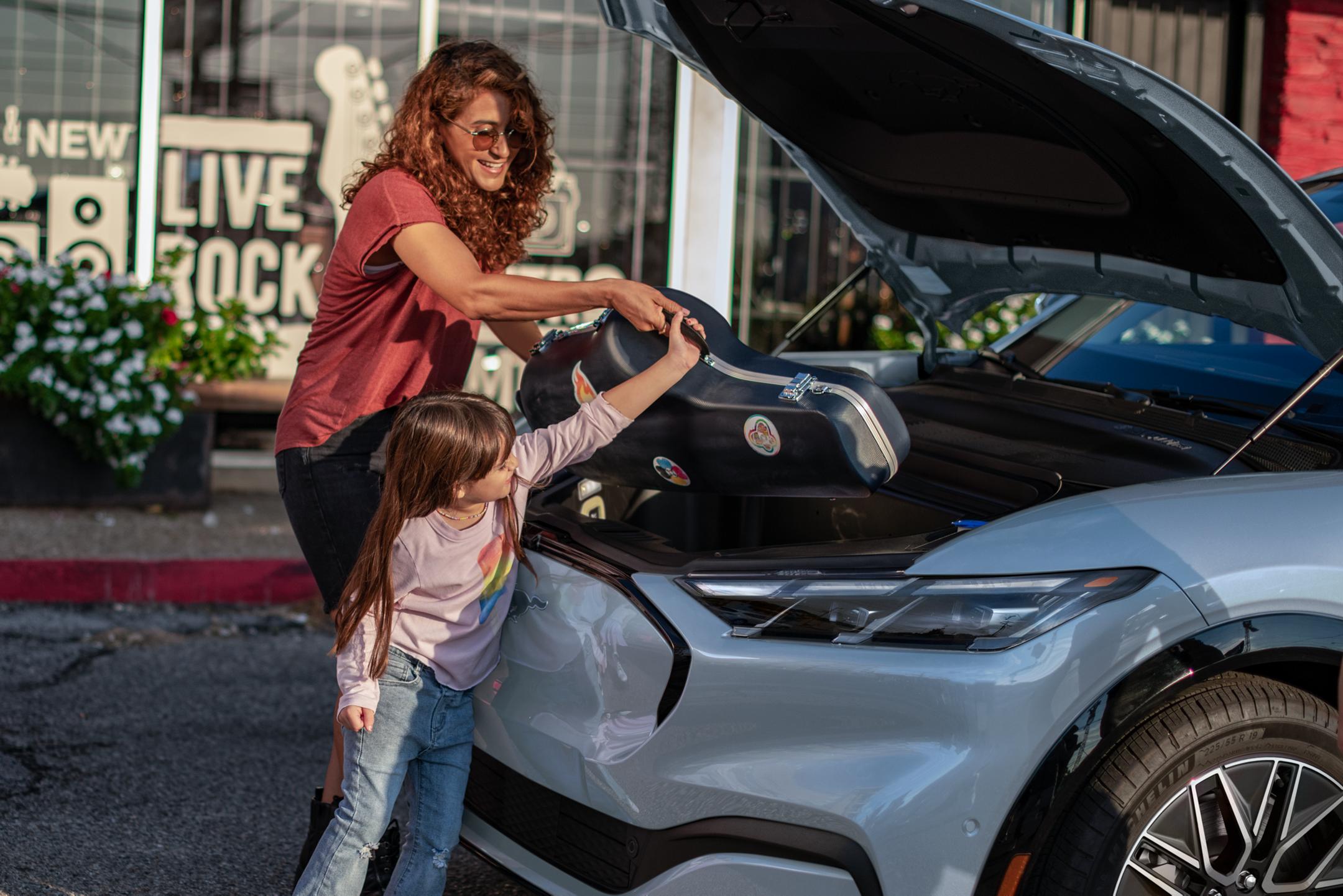 Les parents et leur enfant rangent des affaires dans le coffre avant d'une Mustang Mach-E.
