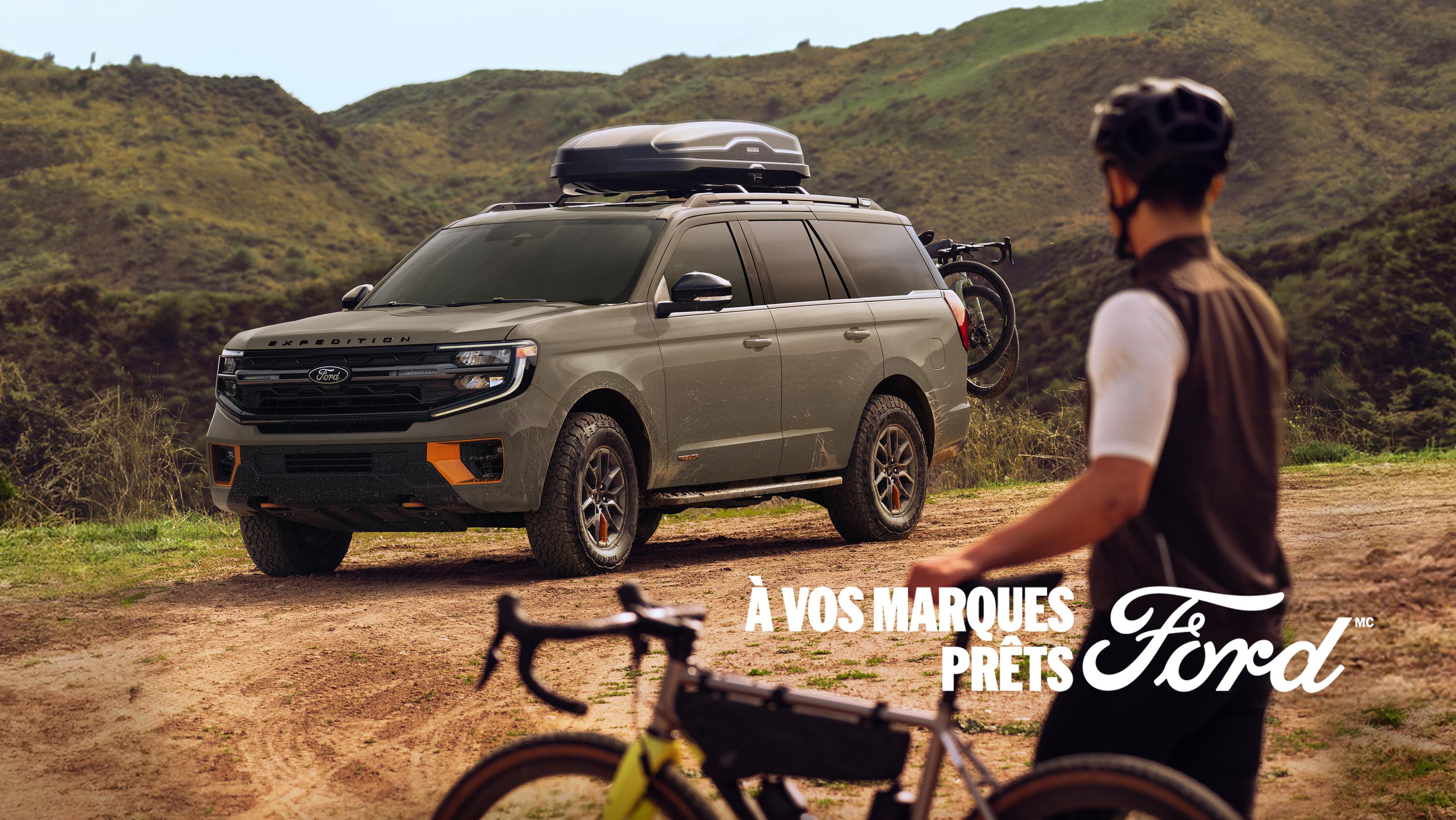 Une personne sur un vélo près d’un modèle Ford Expedition® Tremor® 2026 stationné avec des accessoires Ford en option