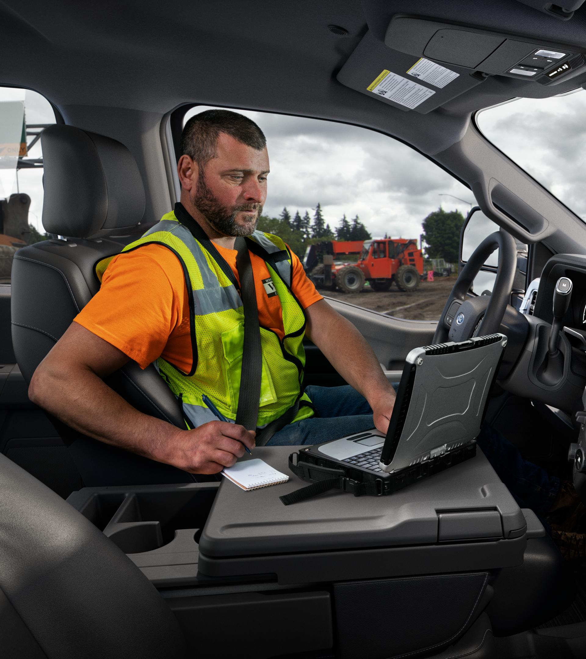 Une personne à l’intérieur de l’habitacle de son Ford Super Duty® 2026 utilisant un ordinateur portable avec la surface de travail intérieure.