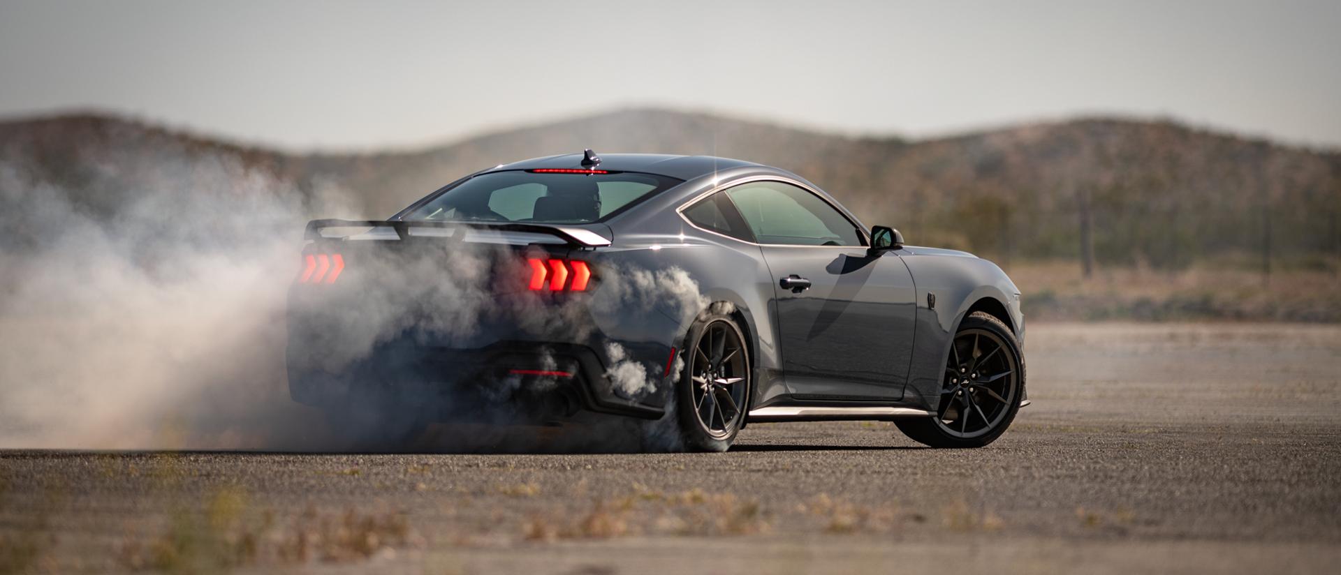 Ford Mustang® Dark Horse™ Coupé 2025 en bleu vapeur métallisé avec un conducteur professionnel faisant crisser ses pneus sur un parcours fermé