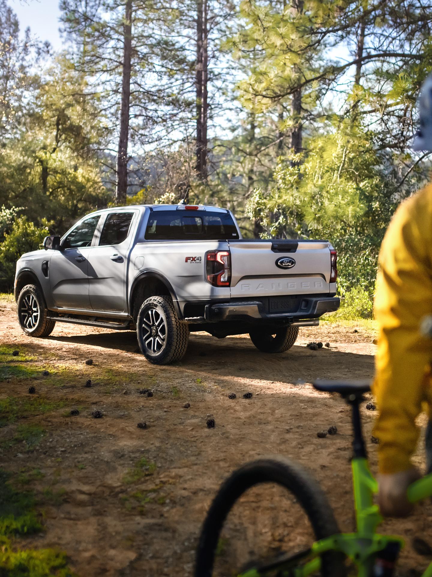 Modèle Ford Ranger® Lariat® 2026 stationné dans les bois. Le propriétaire du camion s’éloigne à vélo