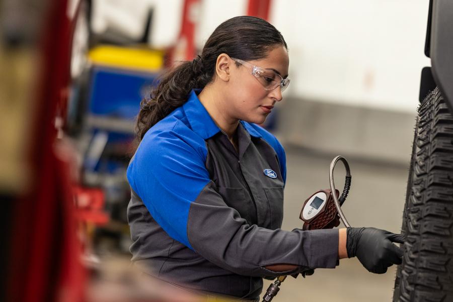 Un technicien de service Ford travaille sur le pneu d’un véhicule surélevé. 