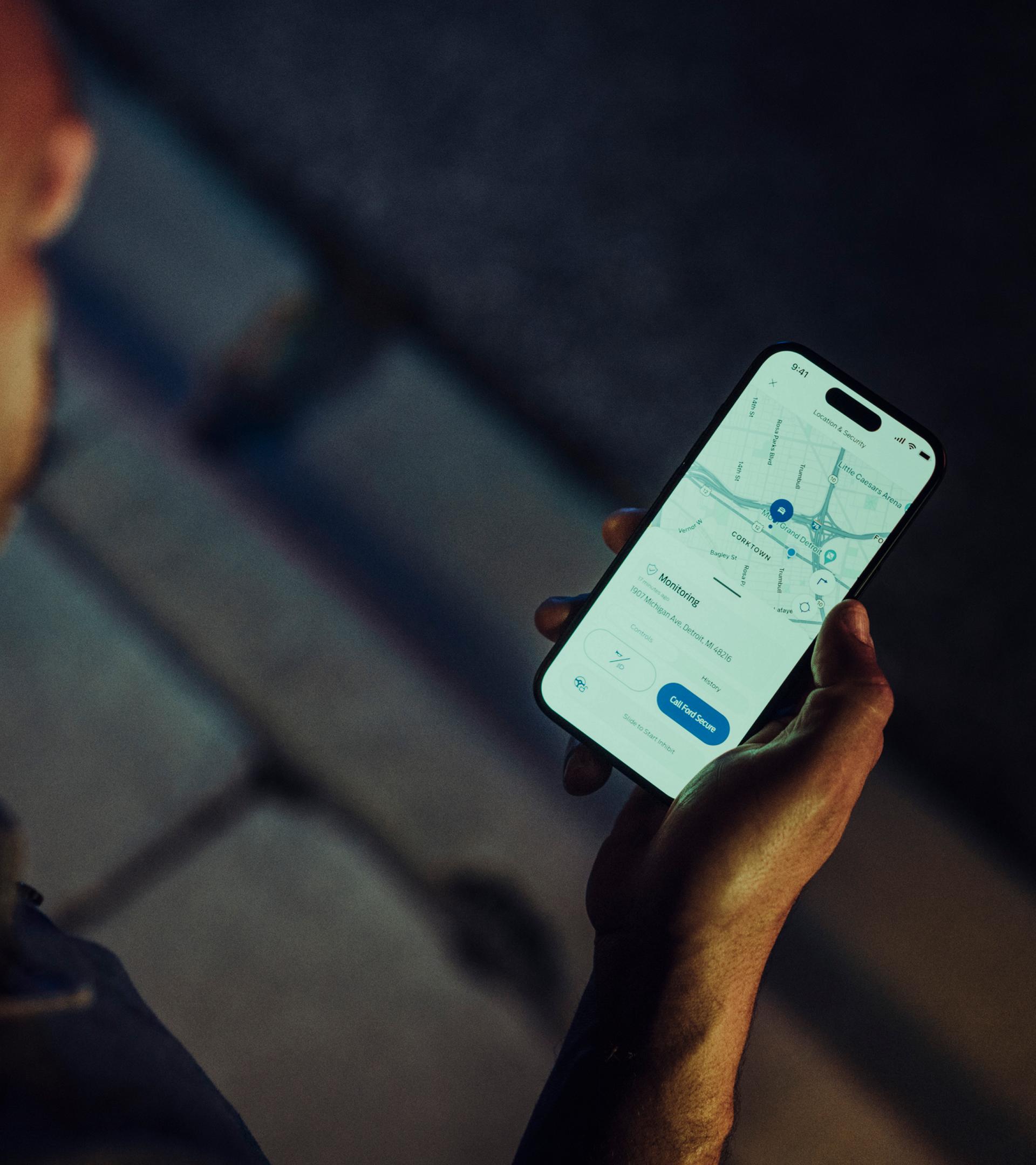 Une personne tient un téléphone intelligent affichant l’écran de localisation du véhicule de l’appli Ford.