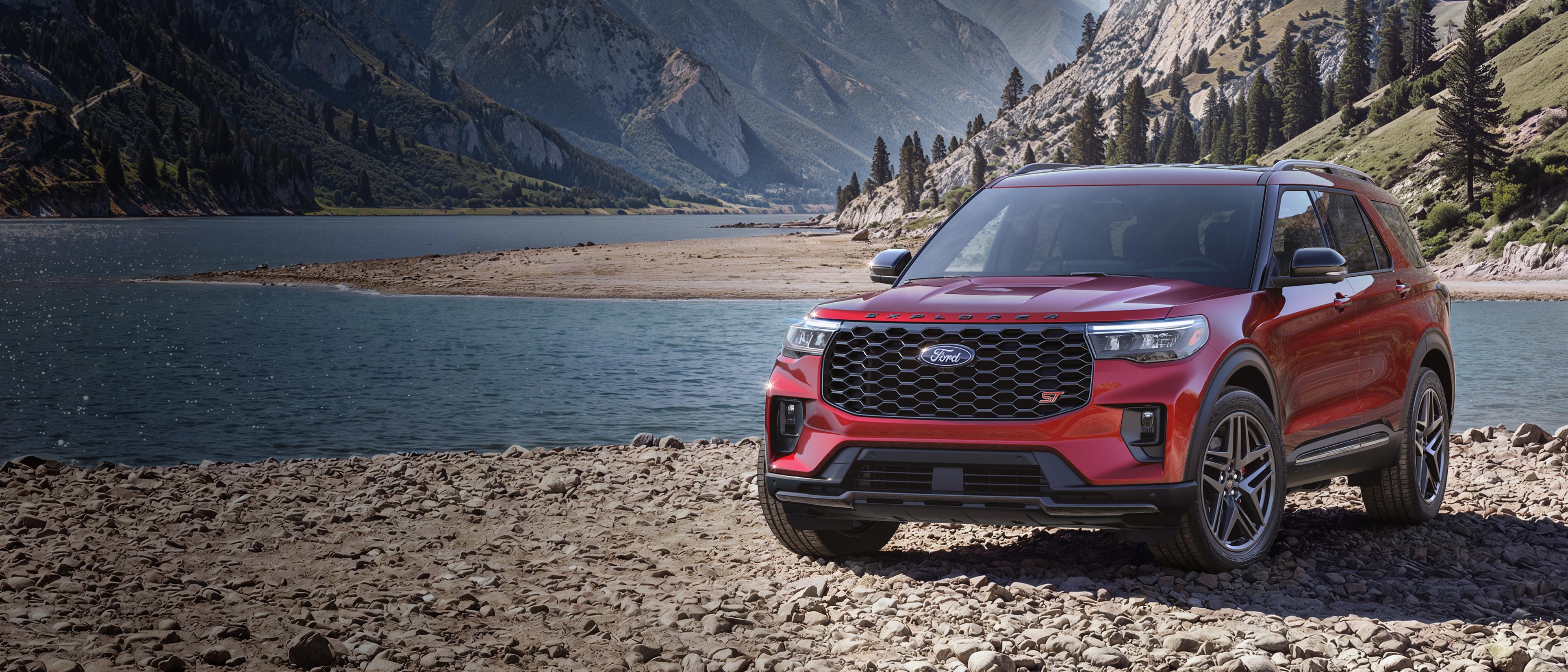 Un modèle Ford Explorer® ST 2027 stationné sur une étendue rocheuse, près d’un lac de montagne