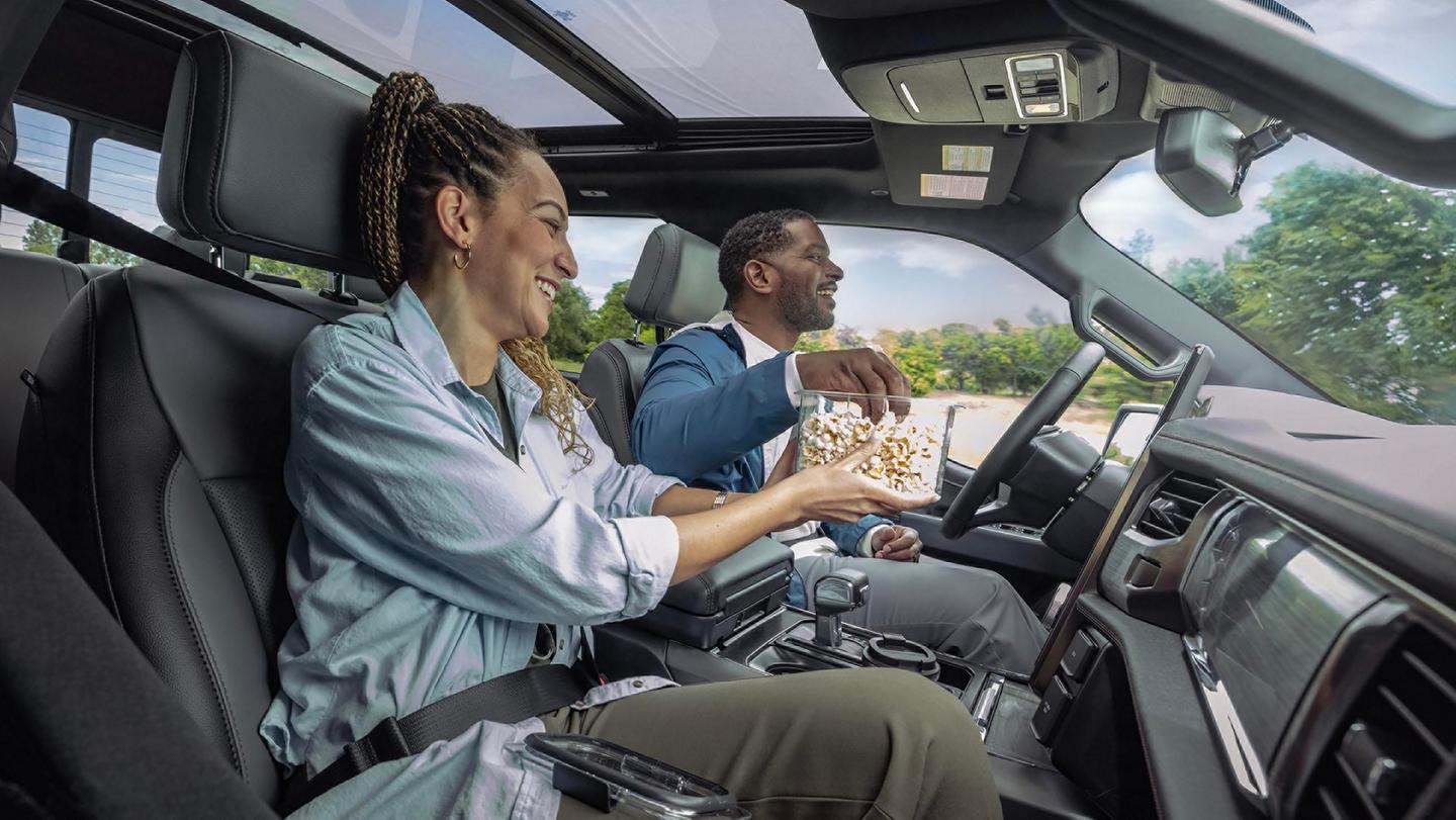 Un conducteur et un passager mangeant du maïs soufflé dans un Ford F-150® Lightning® 2025 engagé avec la fonction BlueCruise