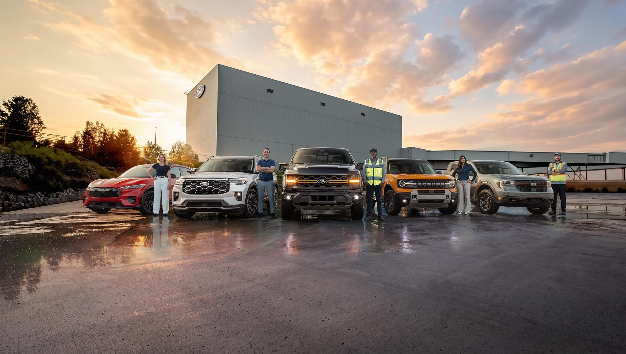 Des employés de Ford debout près de véhicules Ford stationnés devant l’usine d’assemblage Ford d’Oakville.