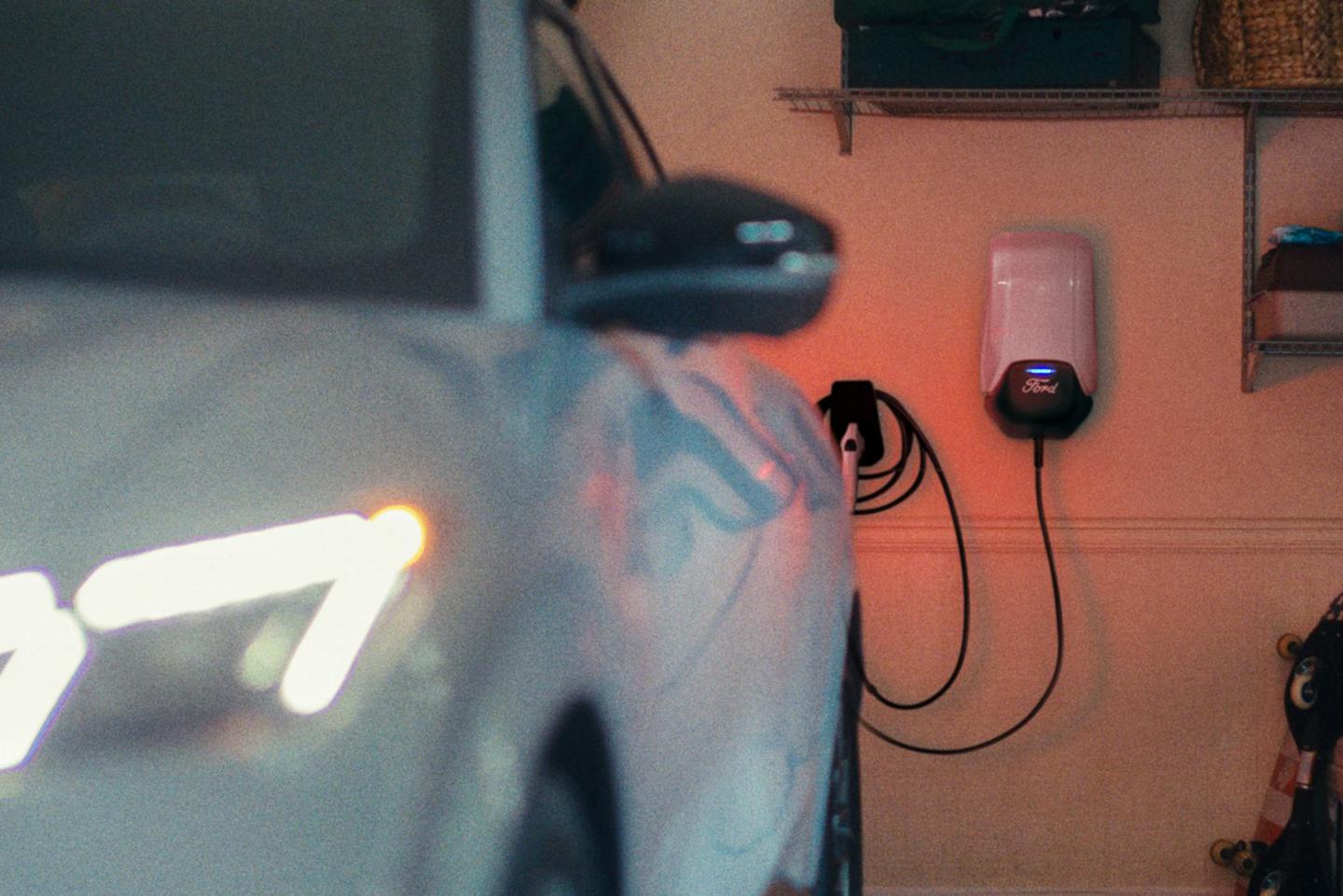 Une Mustang Mach-E garée et branchée à une borne de recharge domestique.