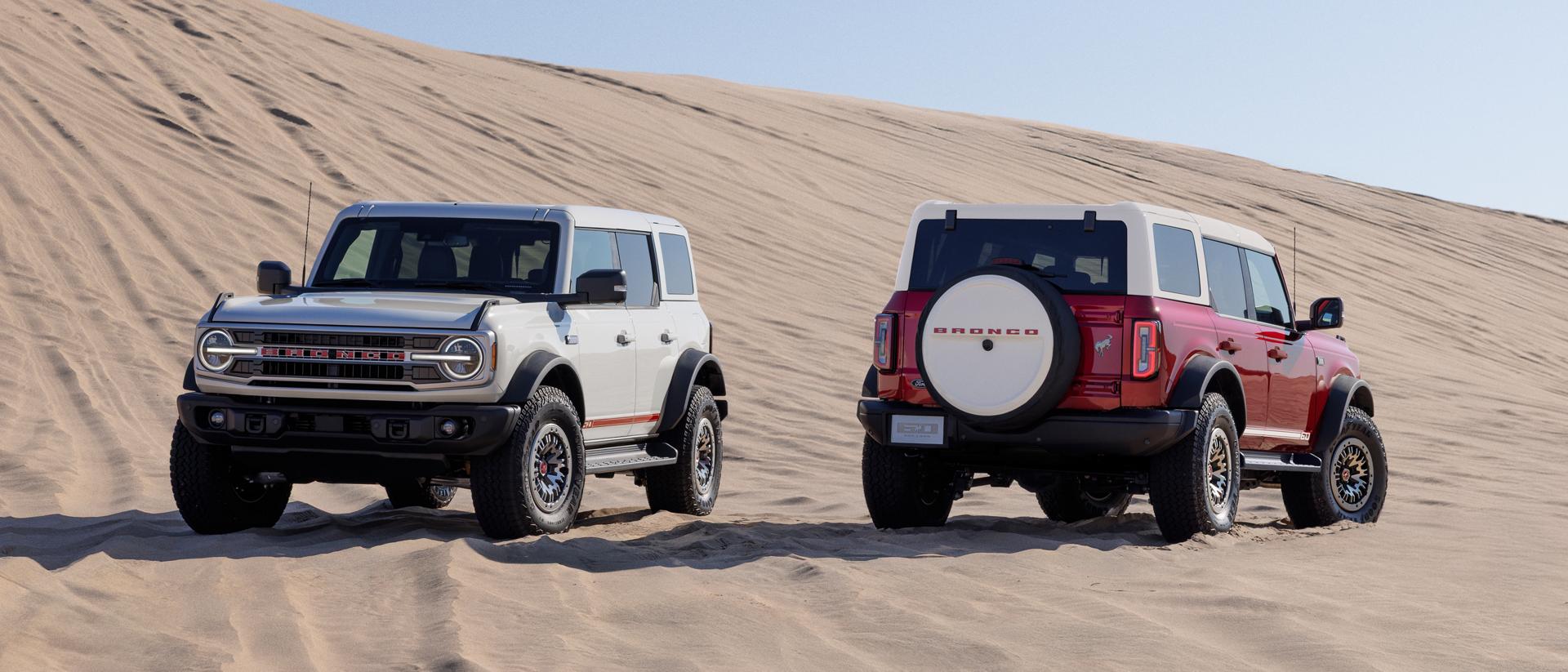 Deux VUS Ford Bronco® 2026 avec l’ensemble 60e anniversaire en option stationnés sur une dune de sable un matin ensoleillé