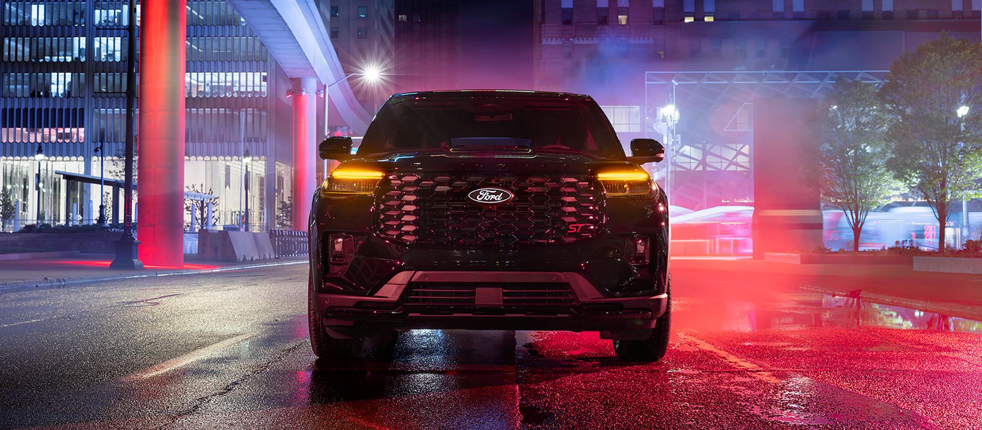 Modèle Ford Explorer® ST 2027 avec l’ensemble Sinister, stationné dans une rue brumeuse la nuit