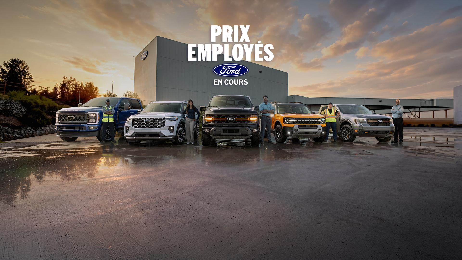Des employés de Ford debout près de véhicules Ford stationnés devant l’usine d’assemblage Ford d’Oakville.