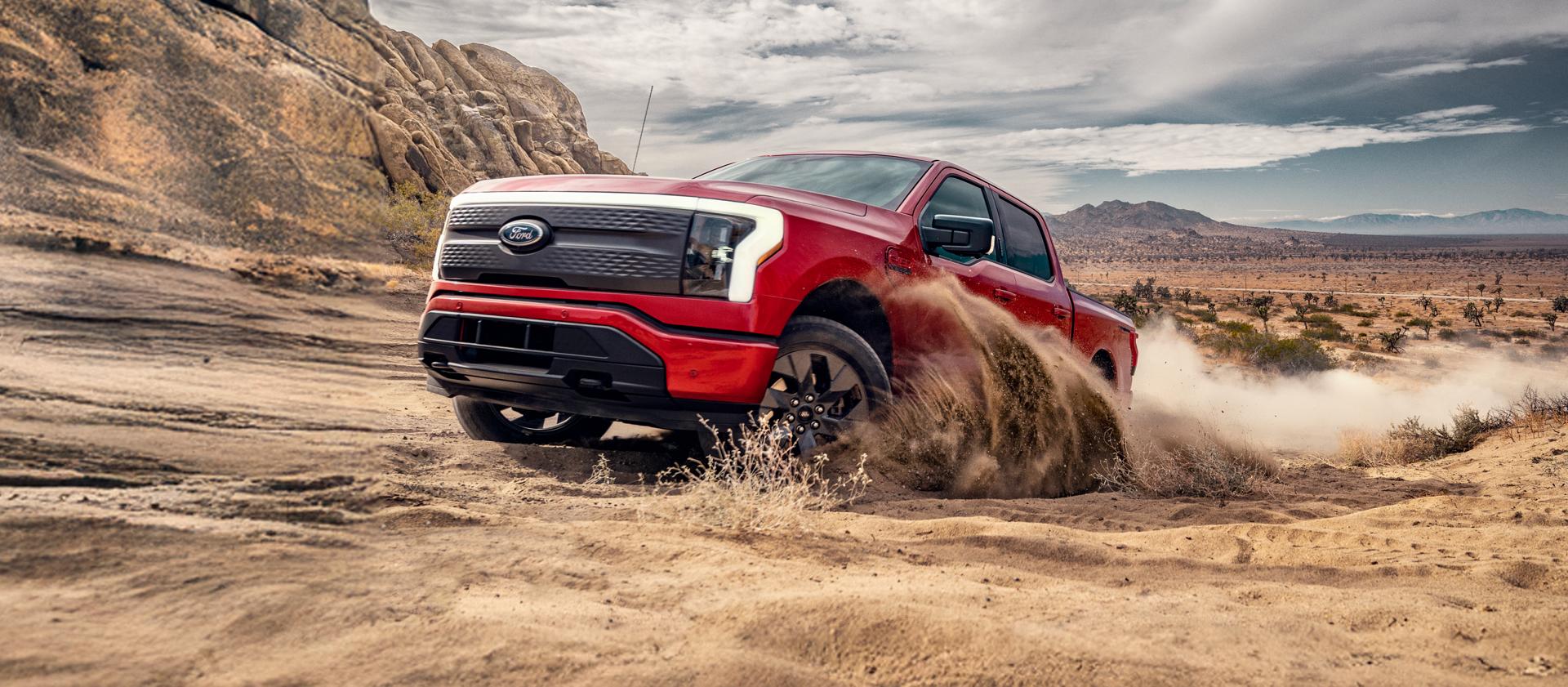 Un F-150 Lightning circulant sur un terrain accidenté et sablonneux.