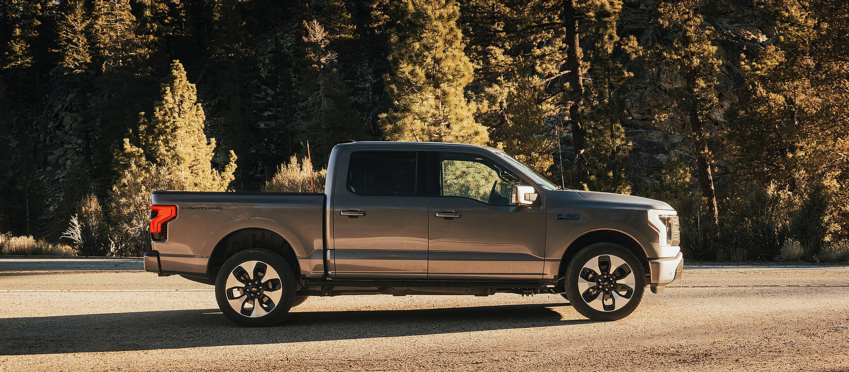 Une vue latérale du Ford F-150® Lightning® 2025 stationné au coucher du soleil dans un endroit pittoresque