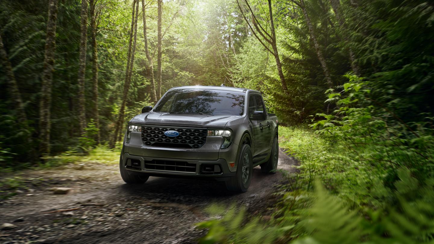 Un modèle Ford Maverick® XLT 2026 avec ensemble hors route FX4® circulant sur un sentier boueux en forêt