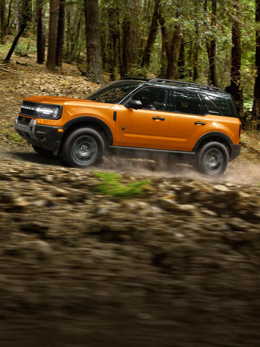 Un Bronco Sport sur une route en forêt.