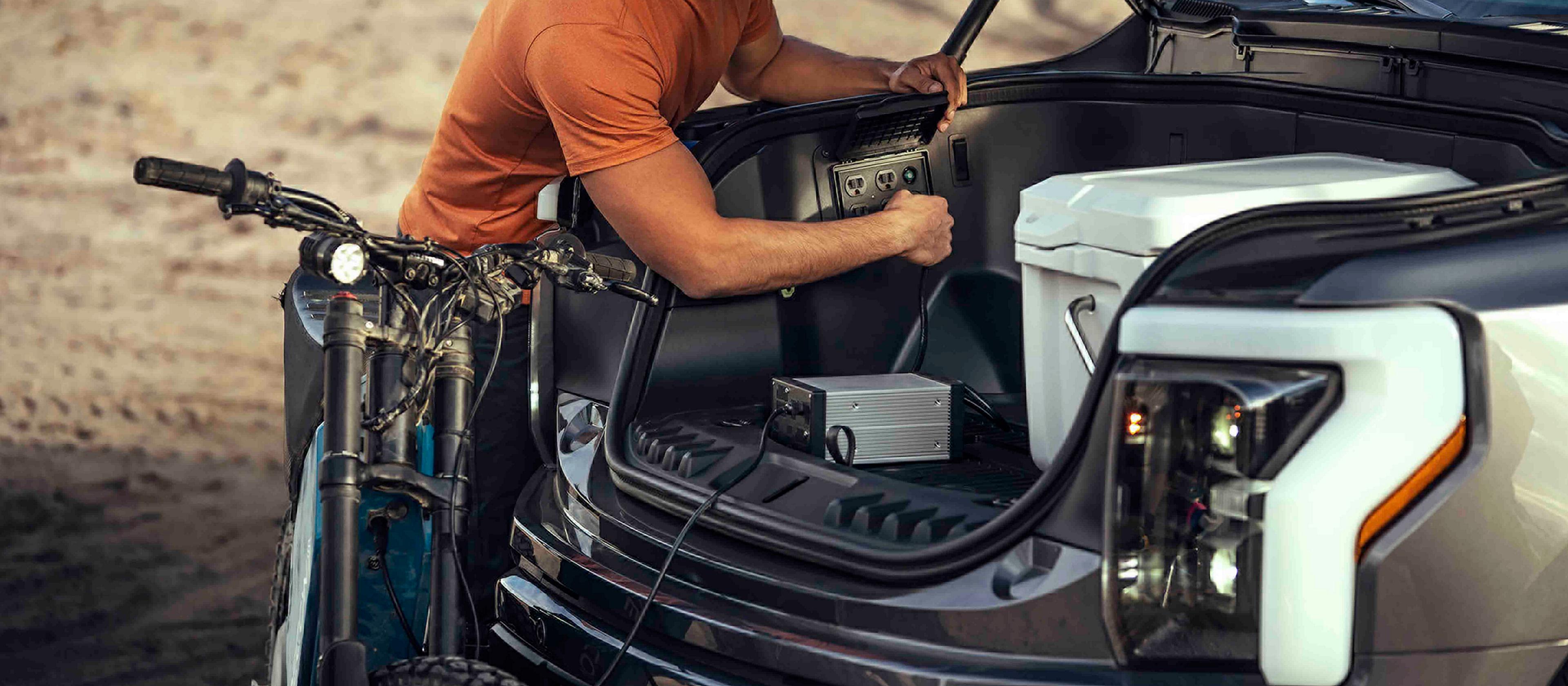 Une personne branchant une moto tout-terrain électrique dans la prise de courant Pro Power Onboard™ de la camionnette Ford F-150® Lightning® 2025