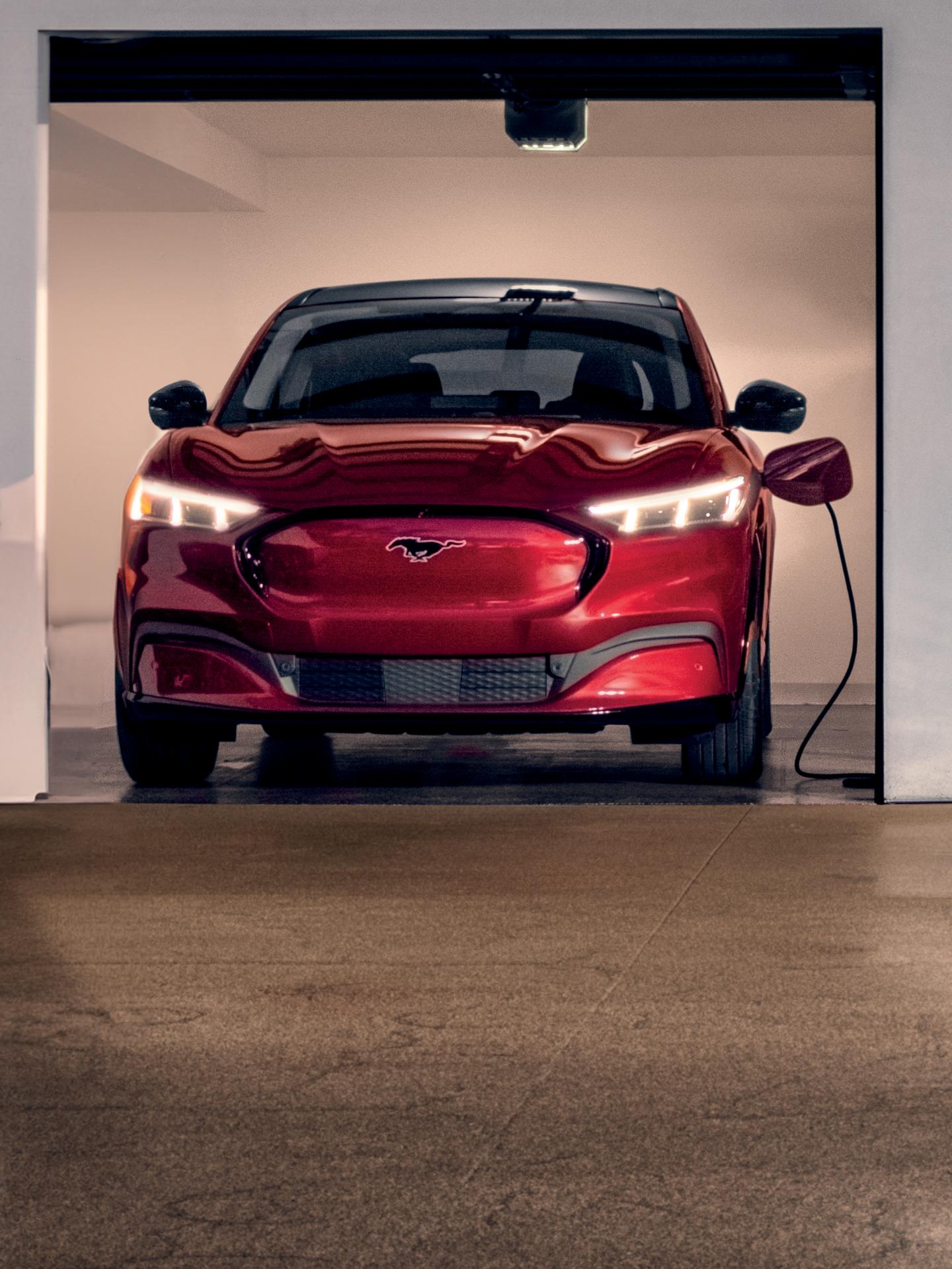 Une Mustang Mach-E garée et branchée à une borne de recharge dans un garage privé.