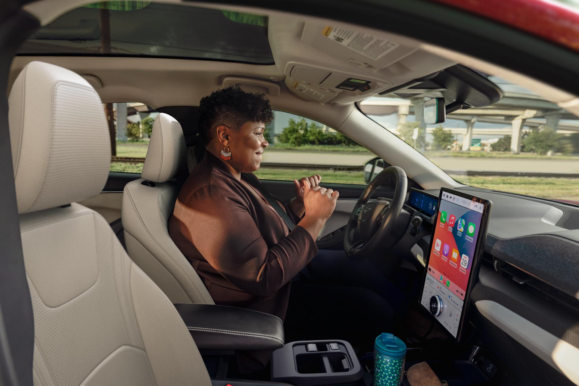 Femme utilisant la conduite mains libres Ford BlueCruise sur une autoroute dans une Ford Mustang Mach-E® 2025