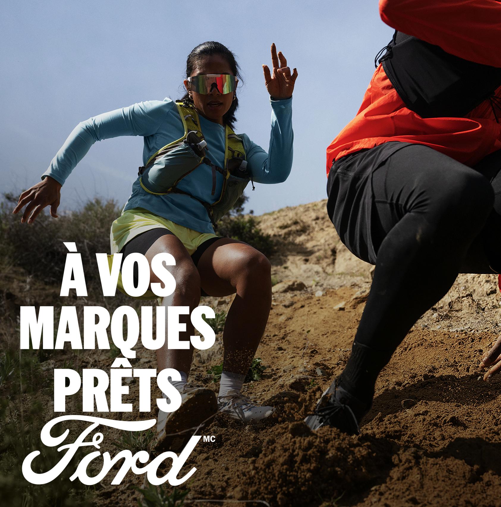 Deux personnes descendant une colline escarpée et boueuse. Le texte blanc « À vos marques. Prêts.Ford » apparaît dans le coin inférieur droit