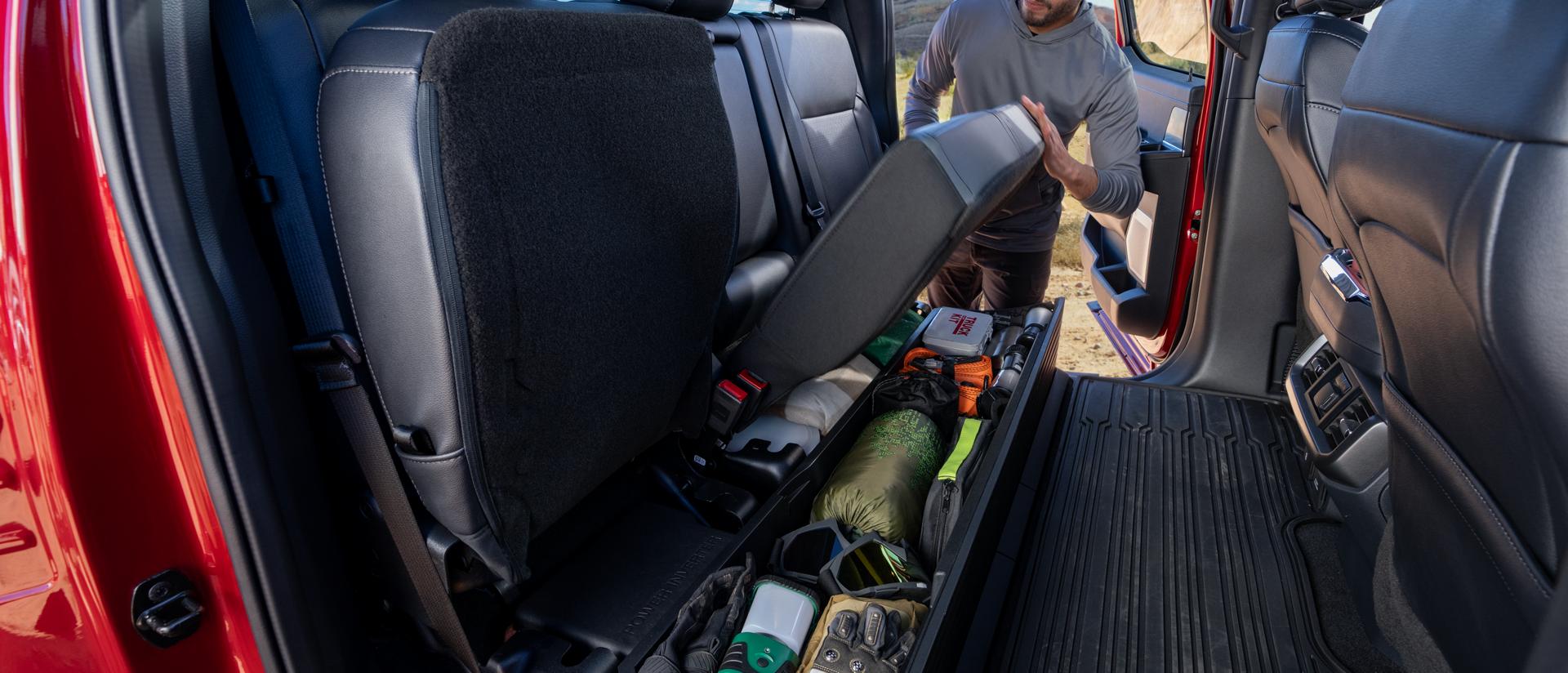 Une personne rabattant le siège arrière montrant la fonction de rangement sous le siège