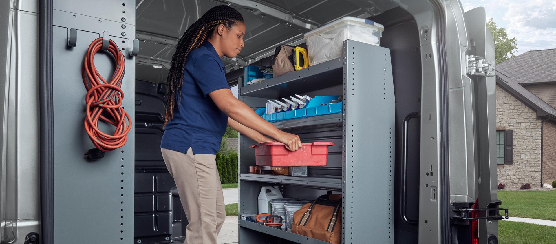 Vue arrière d’un artisan travaillant à l’intérieur des portes arrière d’une fourgonnette Ford Transit® 2027