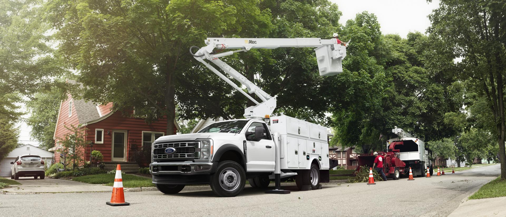 Un Ford Super Duty® à châssis-cabine 2026 blanc équipé d’une rallonge de flèche et d’un coffre utilitaire pour l’élagage des grands arbres.