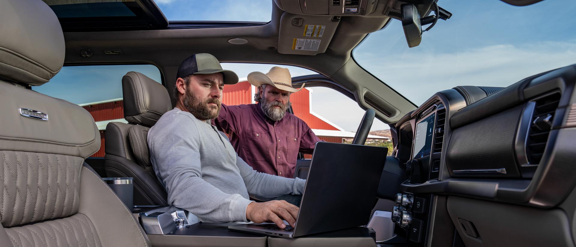 Une personne travaillant sur un ordinateur portable en utilisant la surface de travail intérieure alors qu’une autre personne regarde de l’extérieur de la cabine 