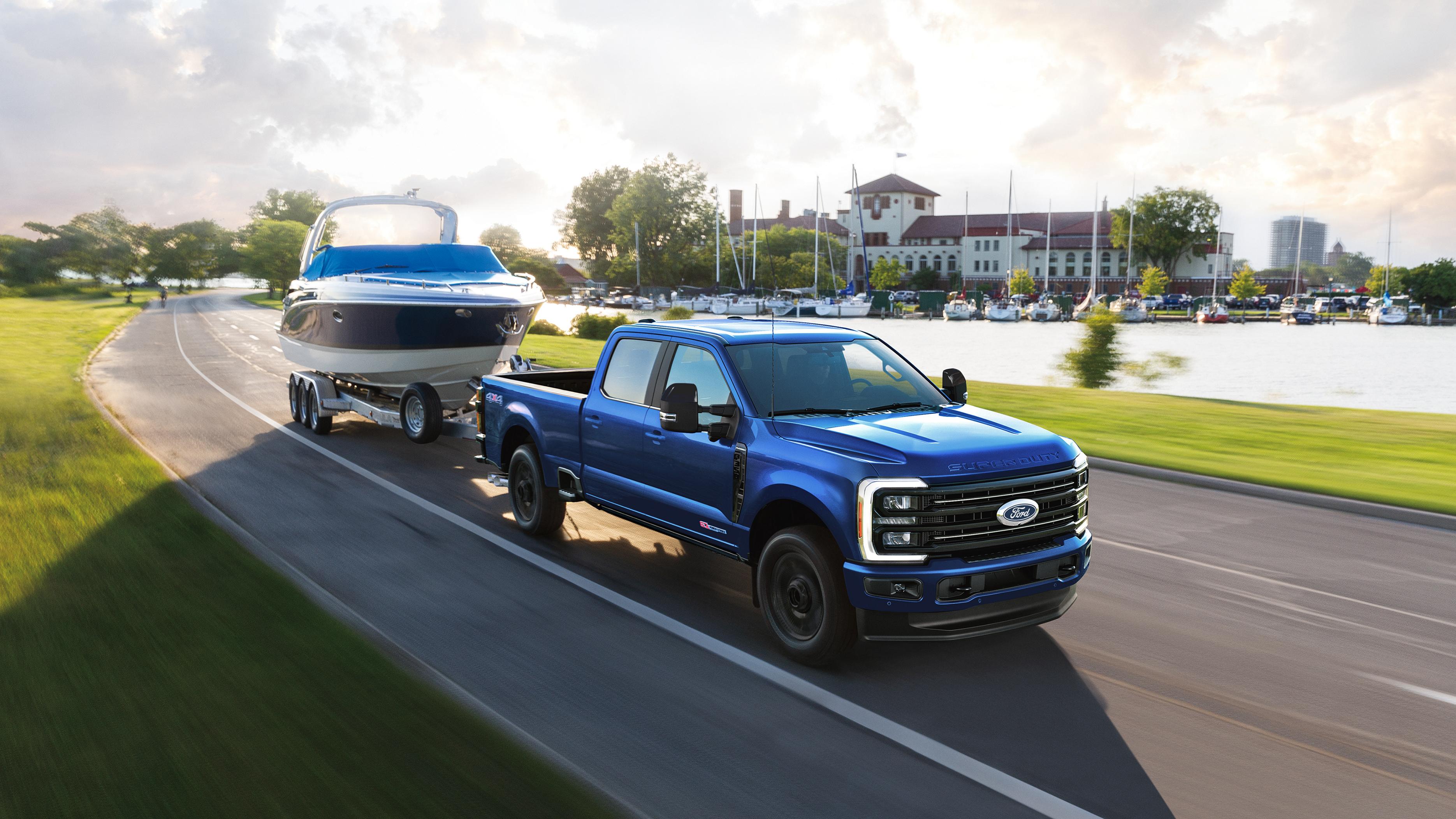 Modèle Ford Super Duty® F-350® Platinum™ 2027 en Bleu neptune remorquant un bateau à moteur sur une route pavée