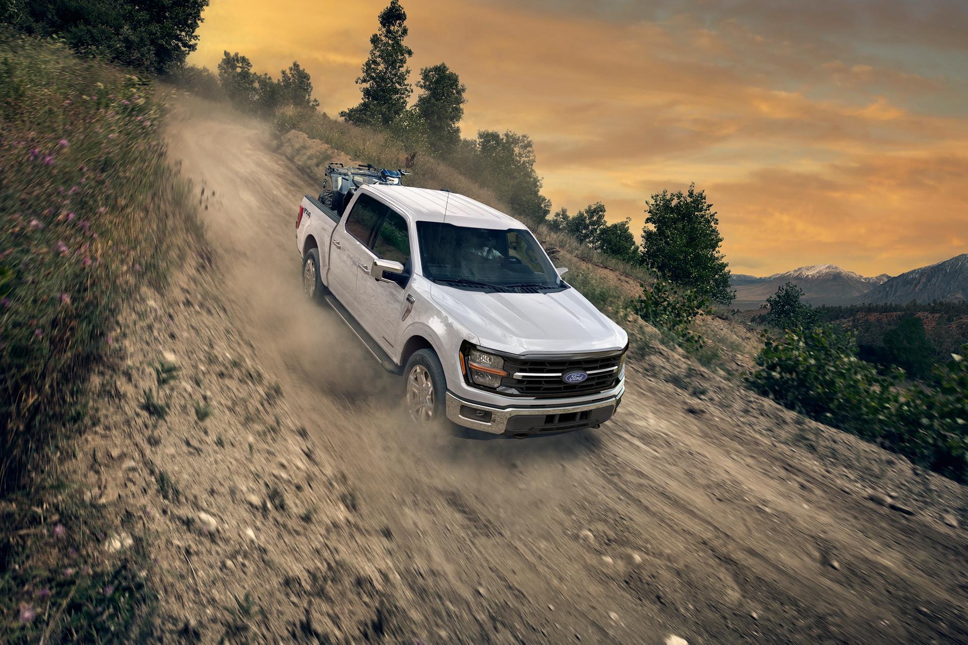 Camionnette Ford F-150® XLT 2026 de couleur blanc Oxford circulant sur une route de terre avec un VTT dans la caisse