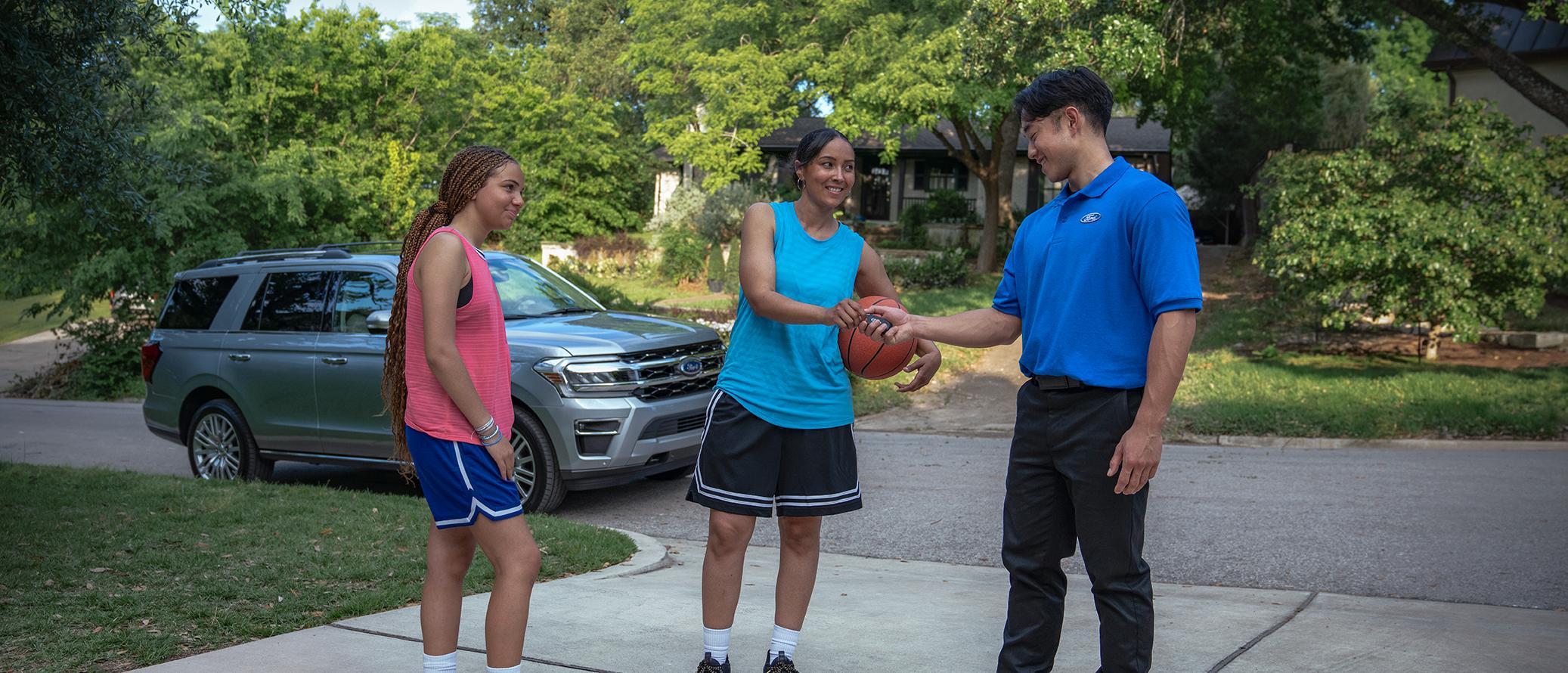 Une propriétaire Ford interrompt une partie de basketball dans son allée pour remettre ses clés à un représentant de Service Ford.