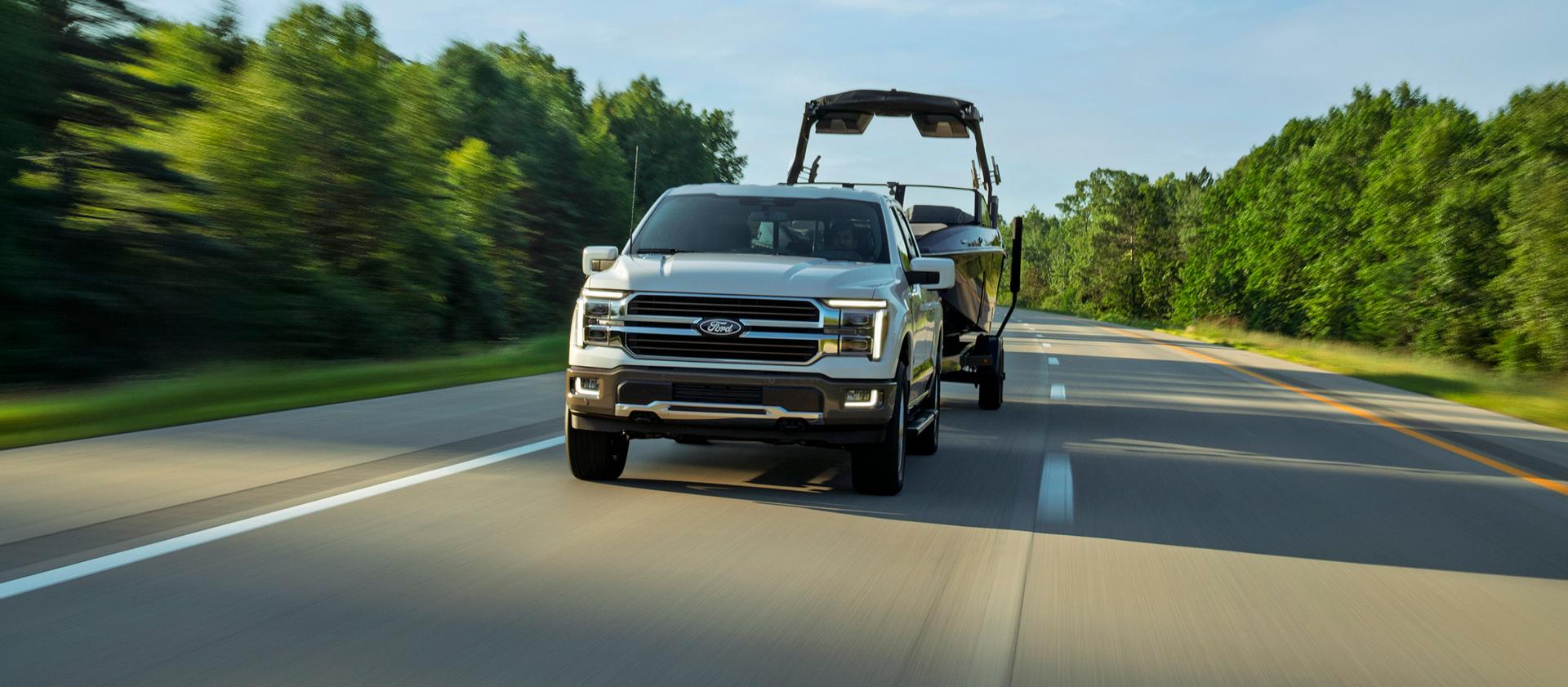 Modèle Ford F-150® King Ranch® 2027 remorquant un bateau sur une route à deux voies