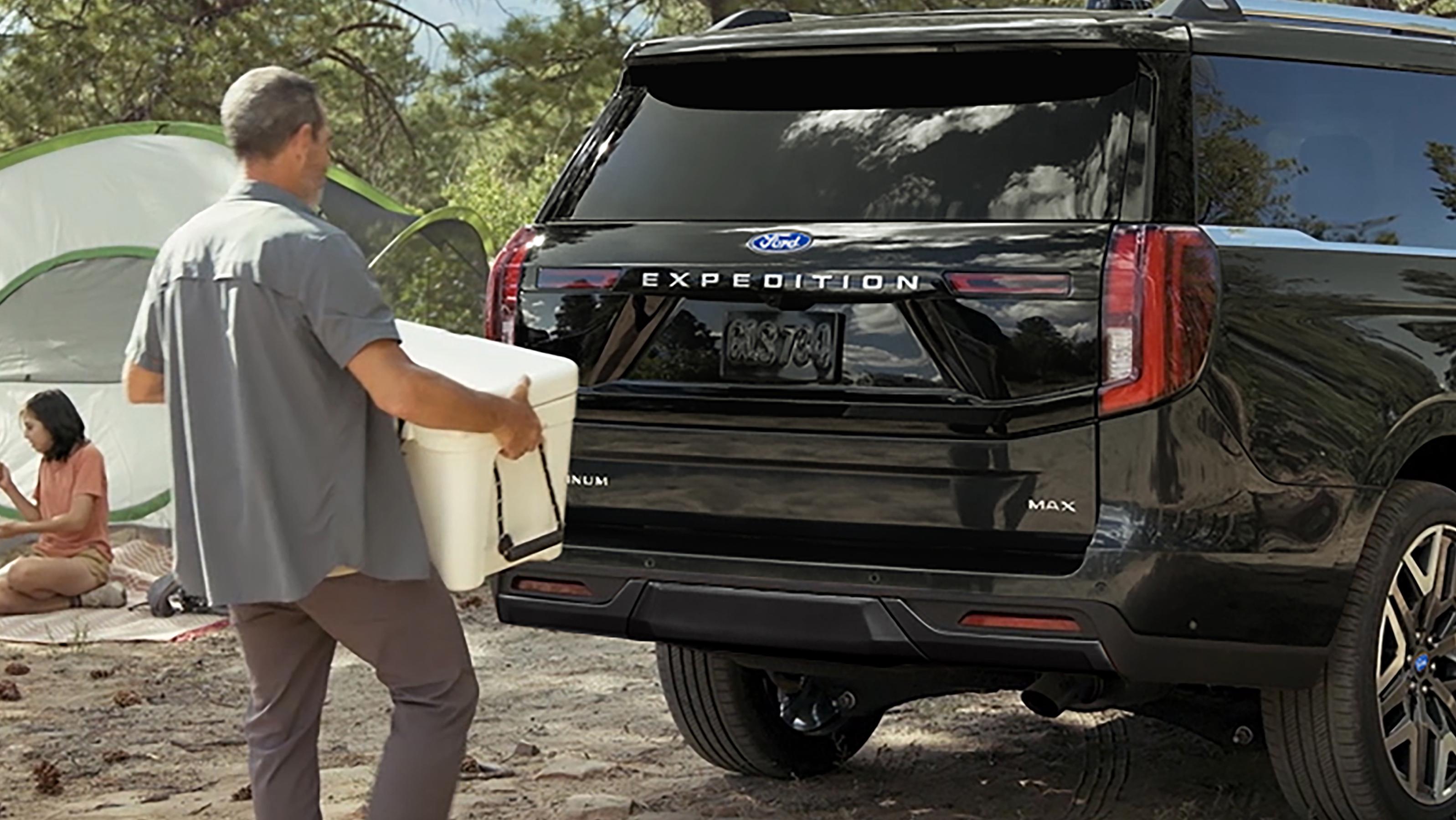 Personne utilisant le portillon divisé Ford avec ouverture à l’approche en option pour charger une glacière dans un VUS Ford Expedition® 2027