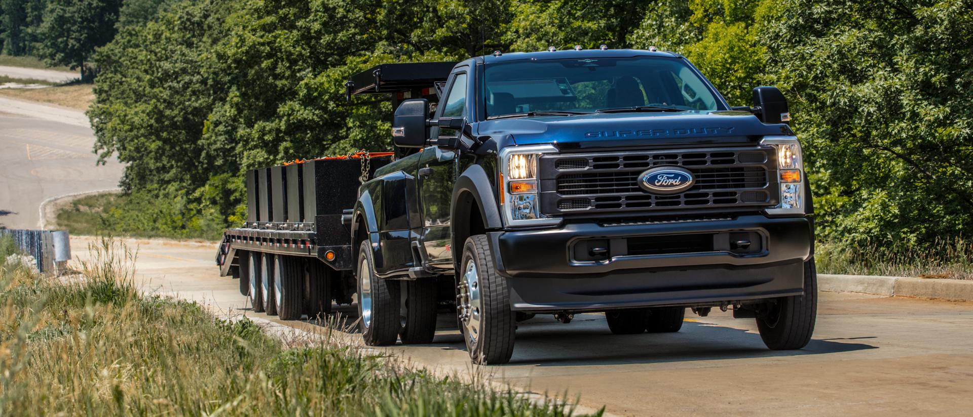 Le Ford Super Duty® 2026 tirant une grande remorque à plateau le long d’une colline pavée.