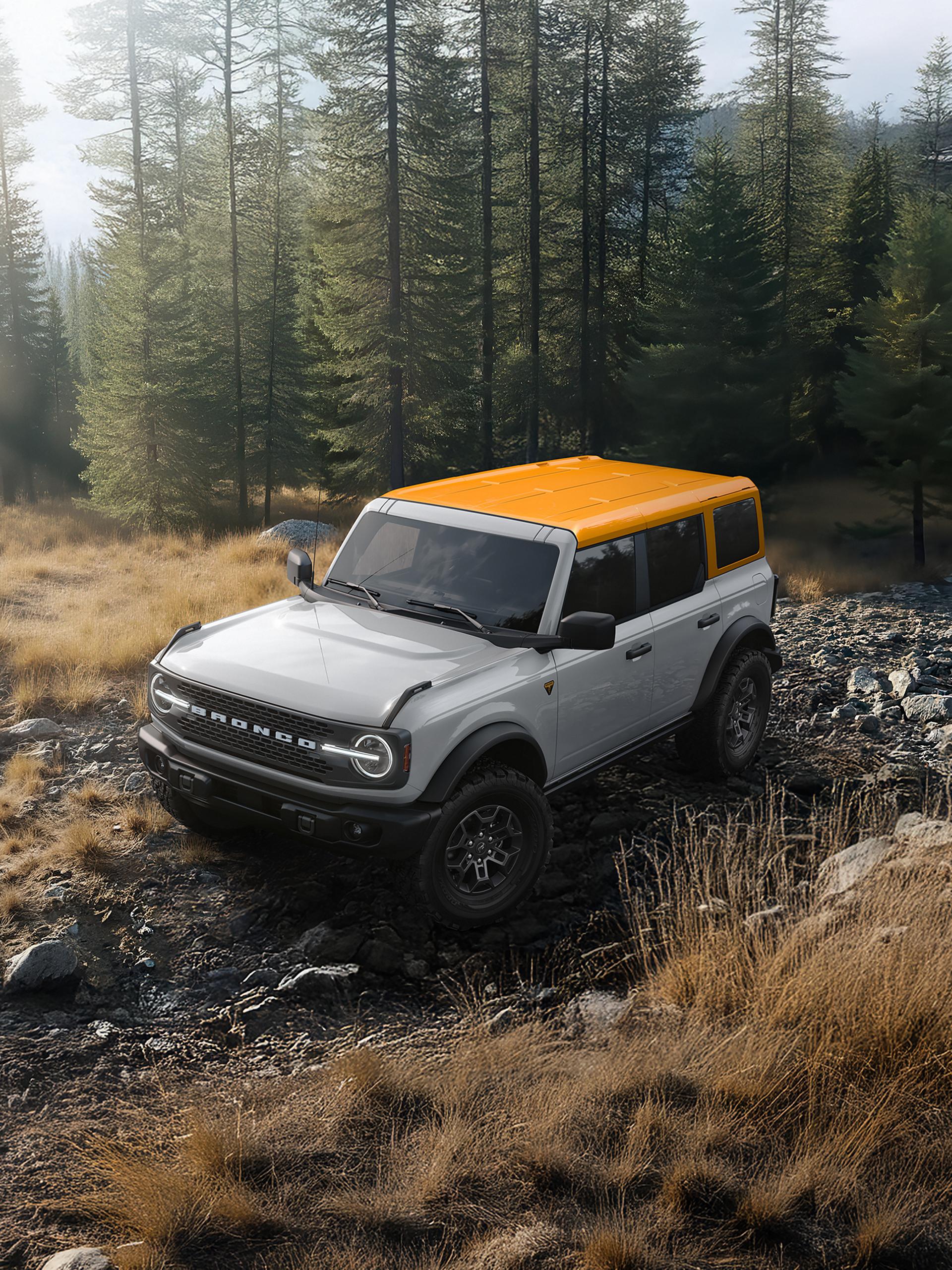 Un VUS Ford Bronco® 2026 sur un chemin boueux, avec une carrosserie de couleur sombre et un toit blanc.