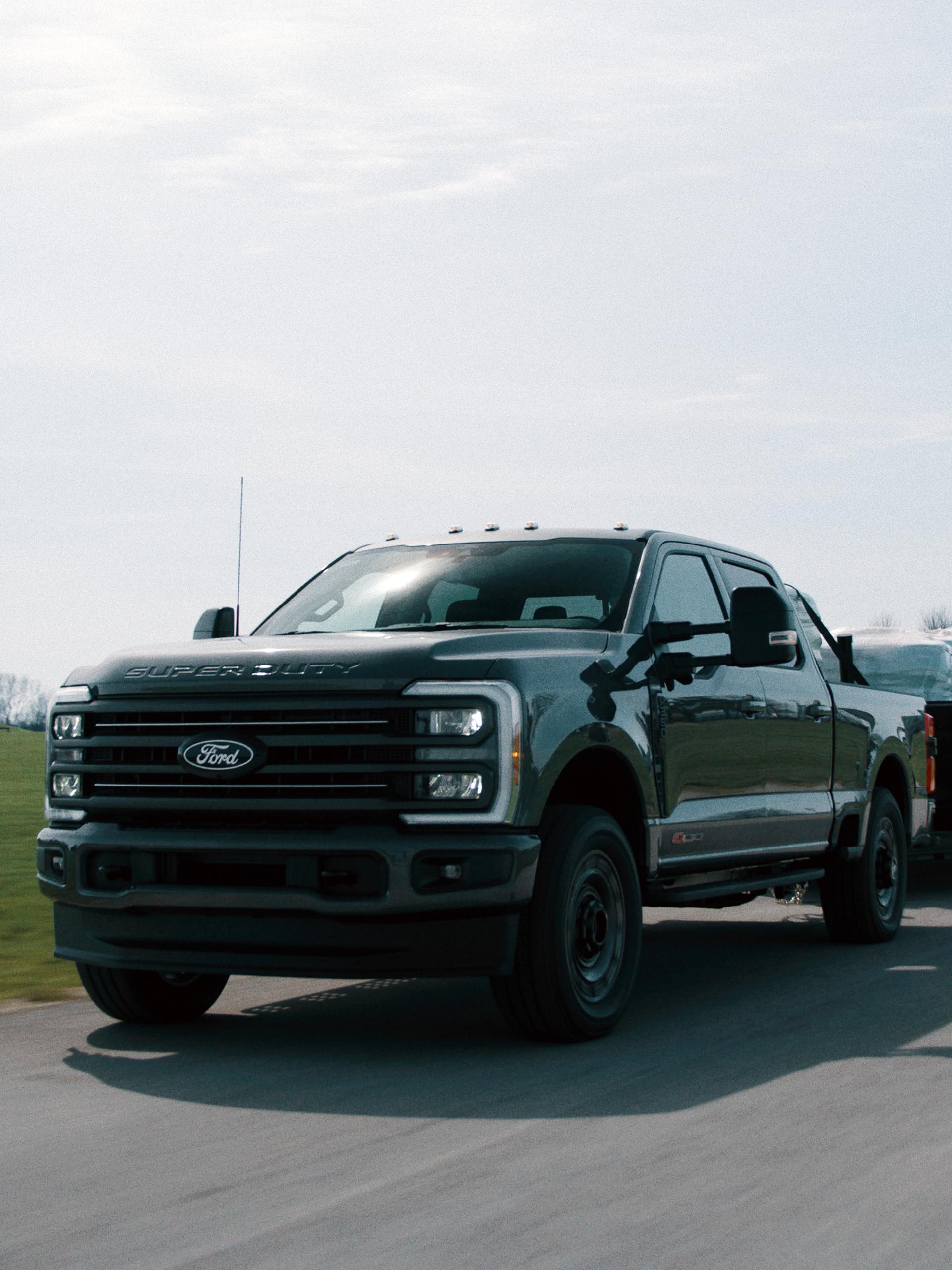 Modèle Ford Super Duty® F-350® XLT 2027 avec l’ensemble Super Duty Carhartt® tirant une remorque à plateau
