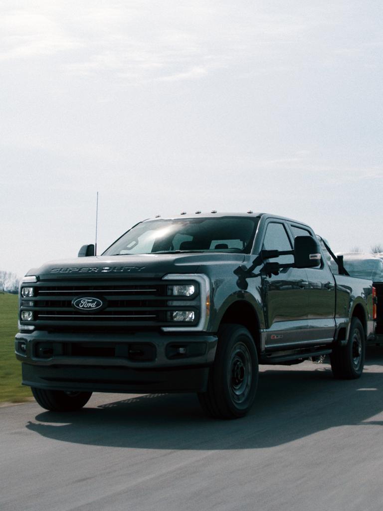 Modèle Ford Super Duty® F-350® XLT 2027 avec l’ensemble Super Duty Carhartt® tirant une remorque à plateau