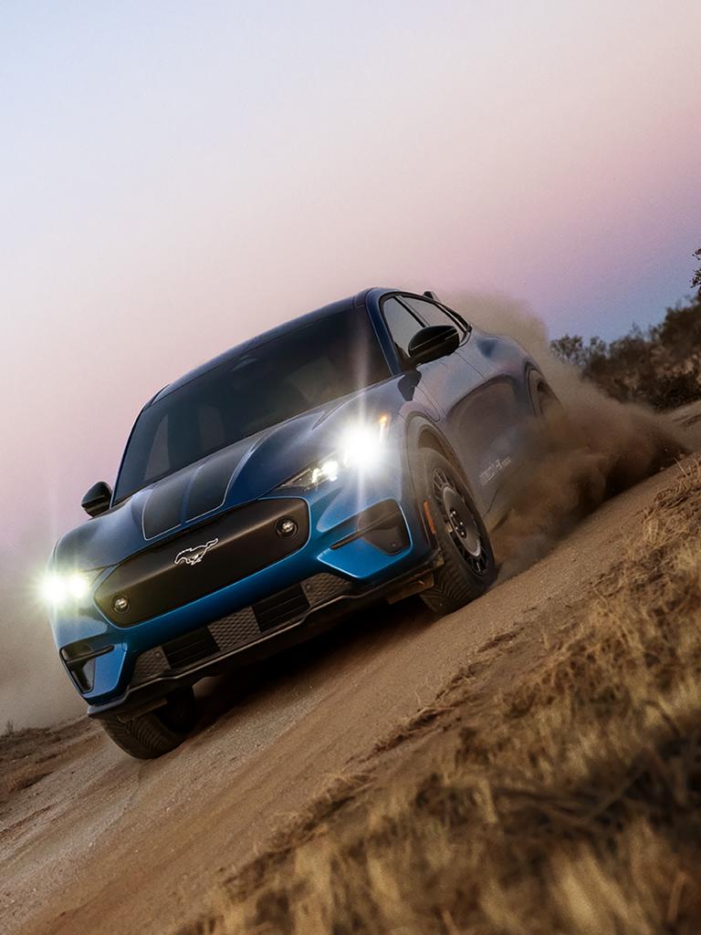 Modèle Ford Mustang Mach-E® Rally 2026 sur une route de terre avec un nuage de poussière